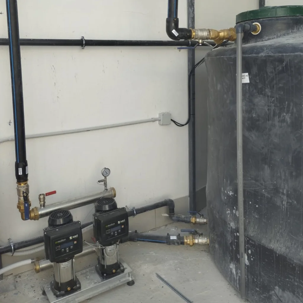 Depósito de agua conectado a dos bombas verticales y tuberías de suministro.
